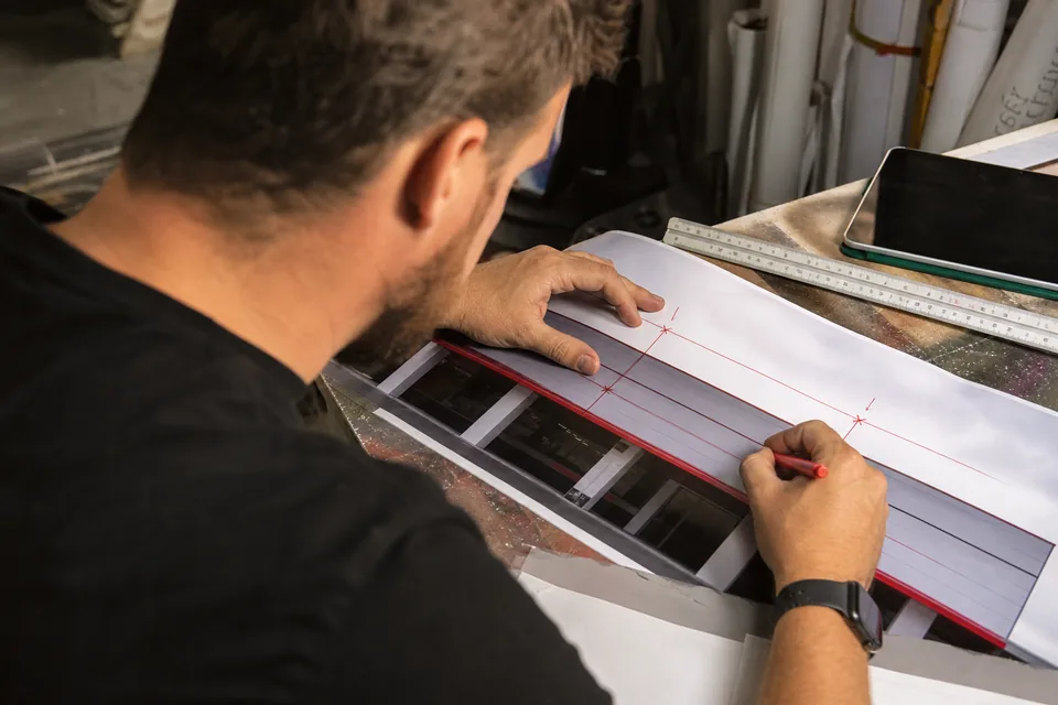 Estimator marking dimensions on a printed site photo next to a tablet