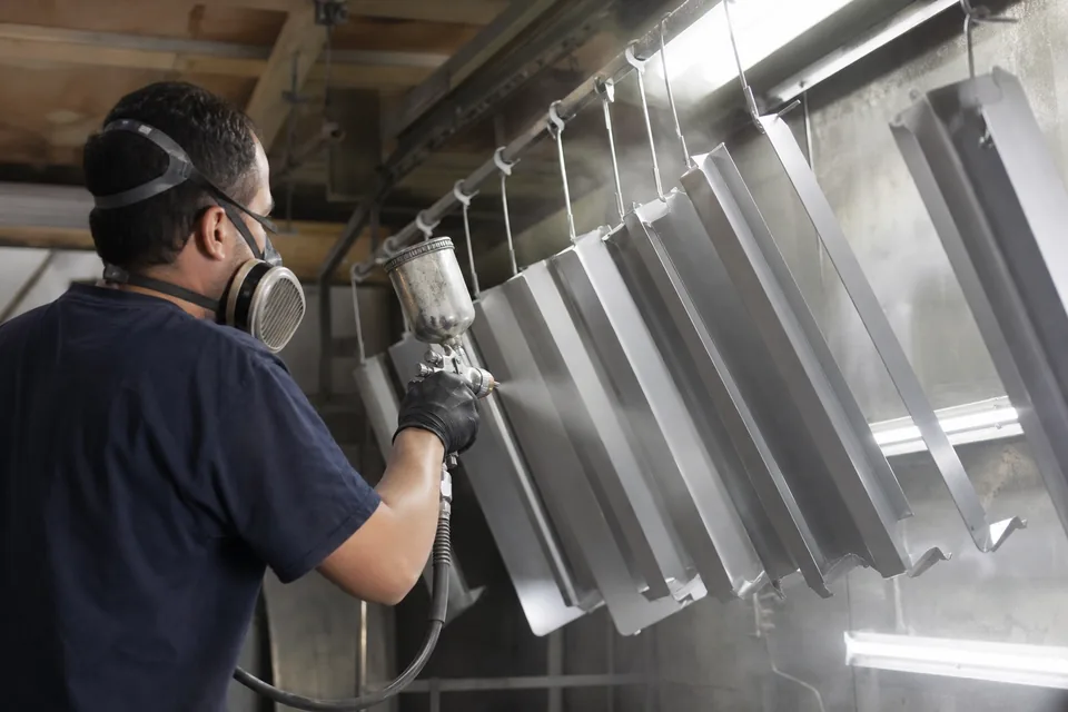 Painter spraying aluminum letter returns in a paint booth